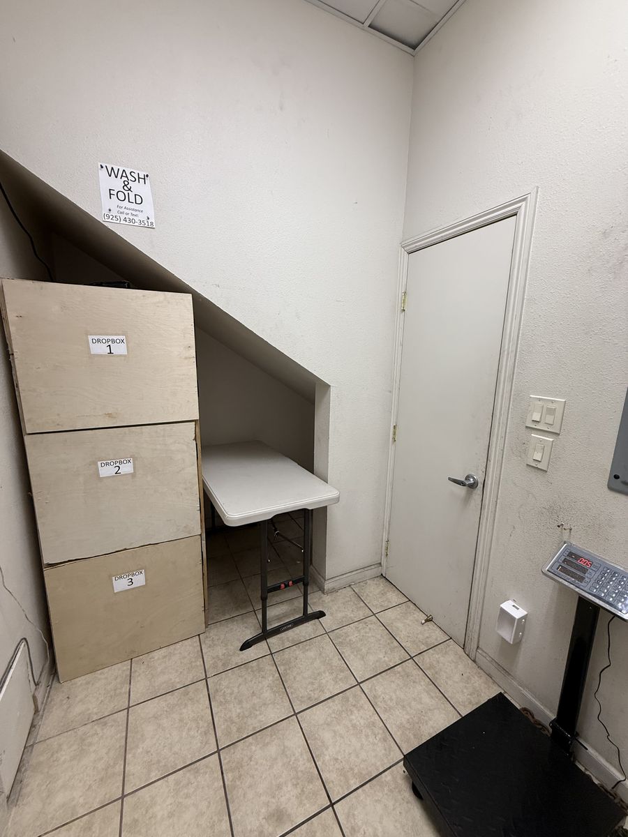 EZ Stop wash and fold area with three numbered drop boxes, a folding table and a floor scale